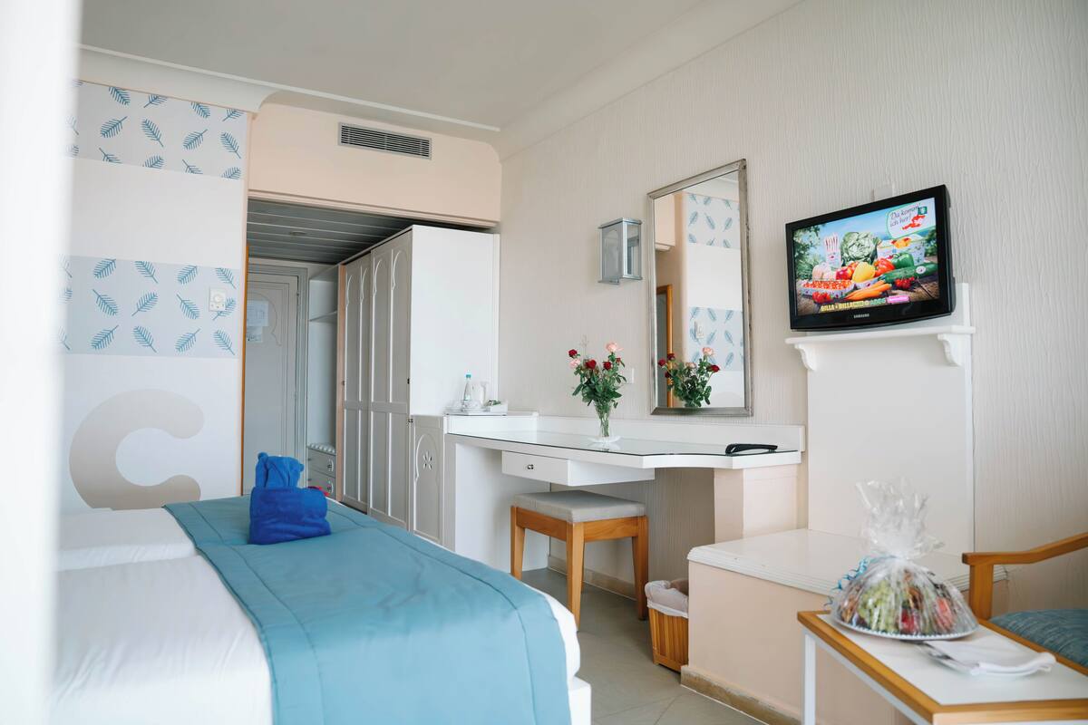 A hotel room with a bed, a desk, a chair, a television, and a bathroom.