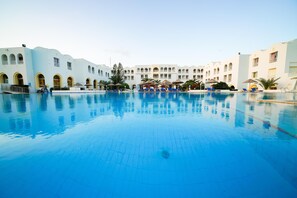Una piscina cubierta, una piscina al aire libre, tumbonas