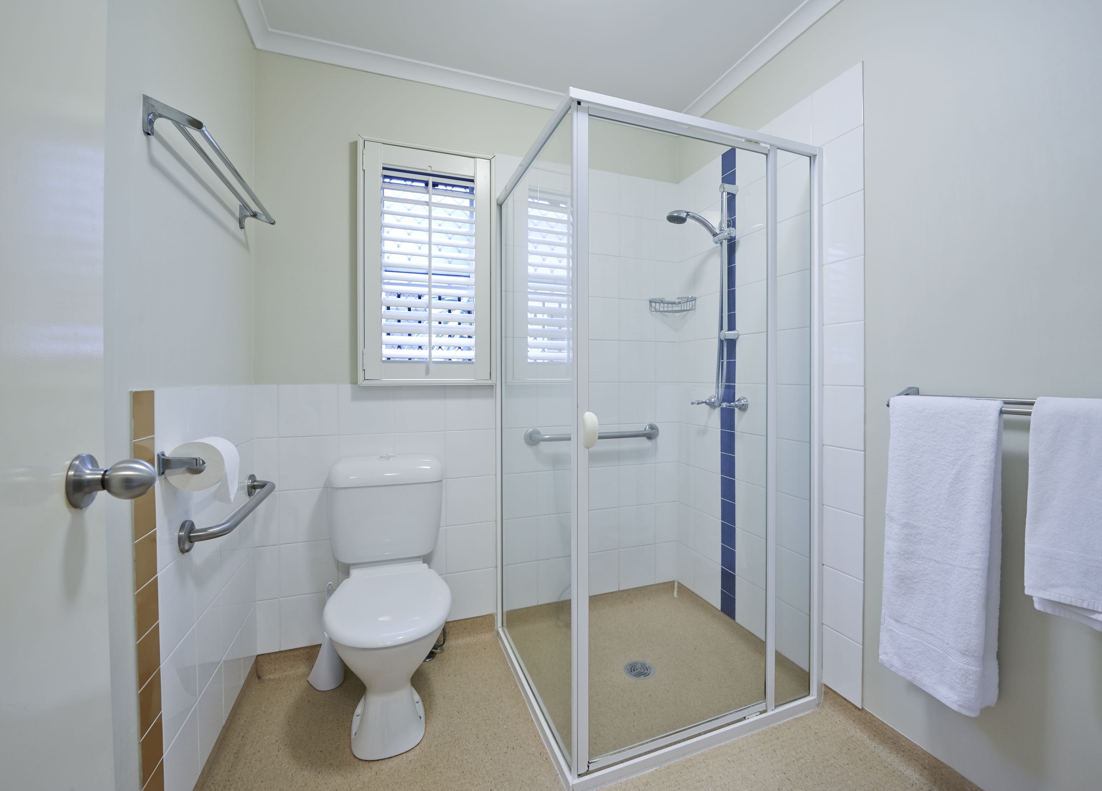 A bathroom with a toilet, a glass shower enclosure, and a towel rack.
