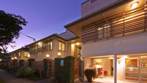 A modern hotel with a reception area, a staircase, and a well-lit entrance. - Brisbane Street Studios (Annerley)