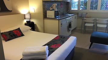 Hotelkamer met een bed, een wasmachine, een magnetron en een kleine kitchenette.