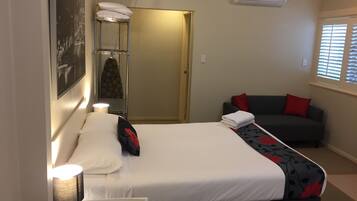 Une chambre d’hôtel équipée d’un lit, d’un canapé, d’une lampe, d’un climatiseur et d’une fenêtre avec des stores.