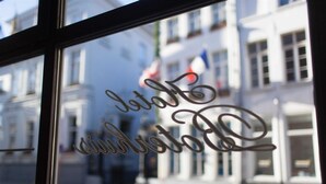 Una ventana con un letrero metálico decorativo que dice "Jardin des Tuileries".