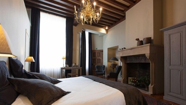 Un dormitorio con una cama grande, chimenea y un escritorio con sillas.