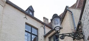 A corner of a building with a window and a street lamp. - Hotel Boterhuis (Bruges)