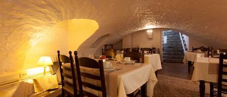 An interior with a vaulted ceiling, tables set for dining, and a staircase leading to an upper level.