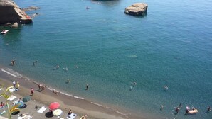 Una playa con agua cristalina, afloramientos rocosos y barcos.