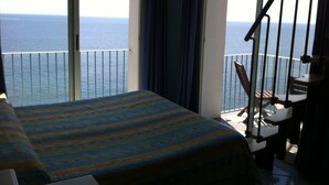 Un balcón con una cama y sillas, con vista al mar.