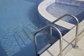 A swimming pool with clear blue water and a metal ladder leading into it. - Hotel Babis (Rethymno)