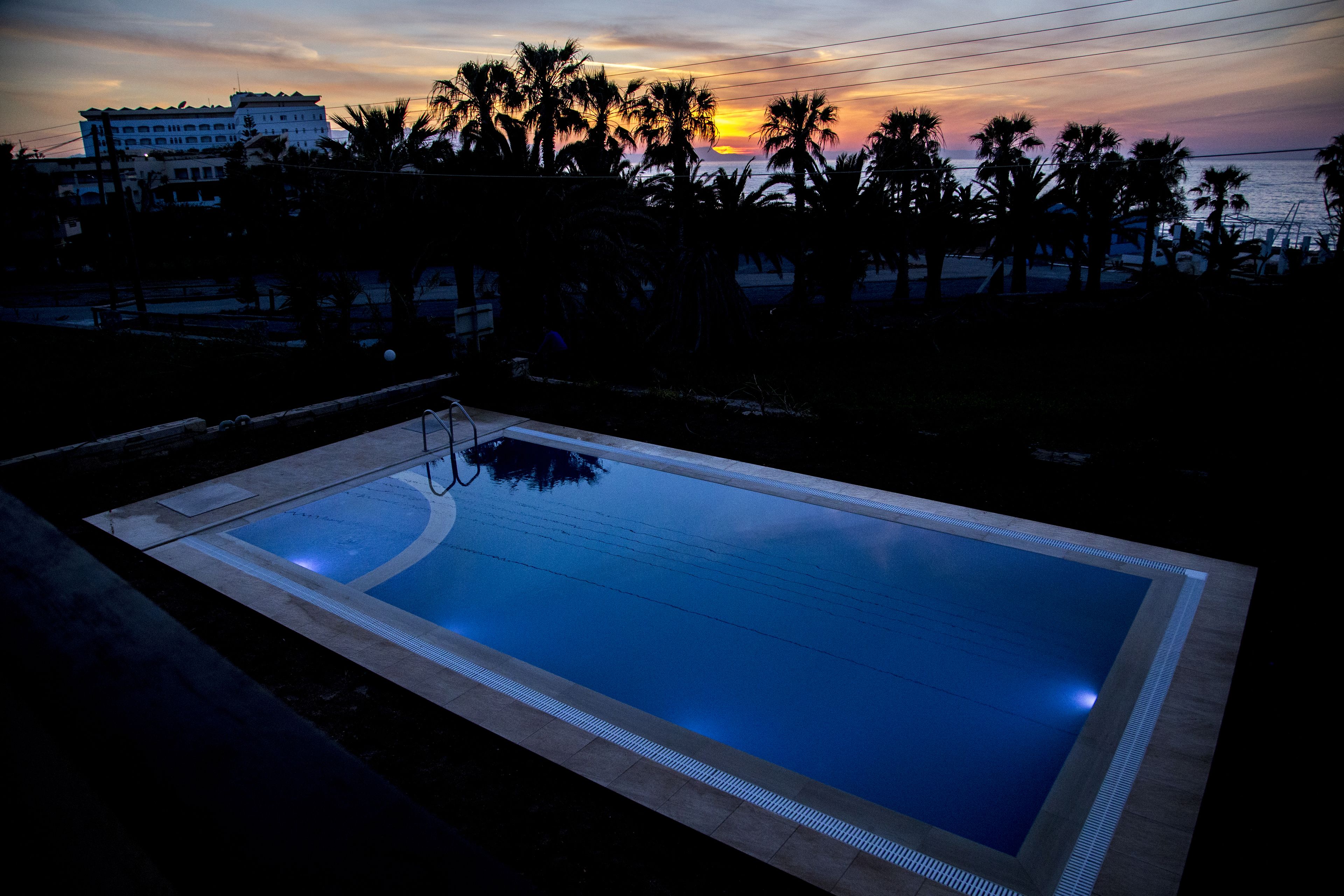 Piscina com vista para o pôr do sol e palmeiras.