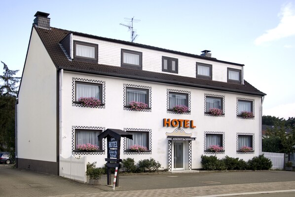 Ein weißes Gebäude mit einem Schild, auf dem 'HOTEL' steht, und einer schwarzen Schautafel mit Text.