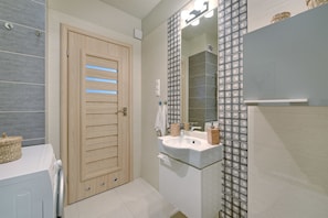 Une salle de bain moderne avec une porte en bois, un lavabo en verre et un mur à motifs.