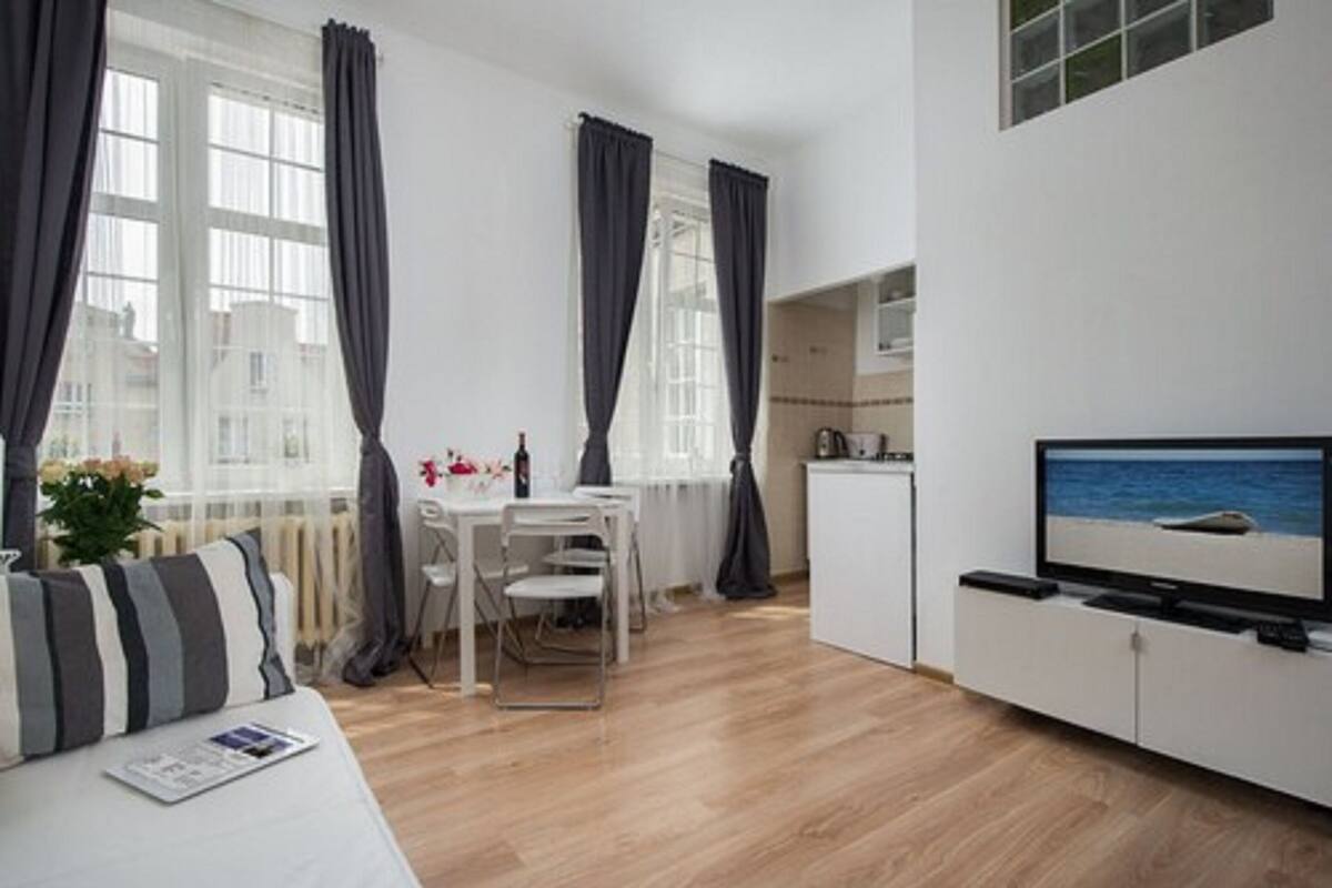 Uma sala de estar moderna com sofá, mesa de jantar e televisão.