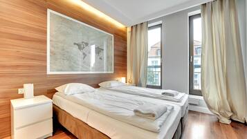 Habitación de hotel moderna con dos camas, cabecero de madera, un cuadro abstracto grande y una ventana con cortinas.