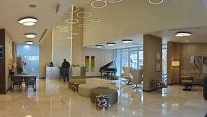 A spacious lobby with a reception desk, seating areas, and a grand piano. - Skyna Hotel Luanda (Luanda)