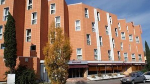 Un hotel de varios pisos con fachada de ladrillo rojo, una entrada central y un letrero que dice "Accueil".