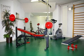 A gym with a bench press, a stationary bike, and a weight rack. - Hotel Toulouse Aéroport (Toulouse)
