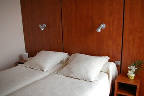 A bedroom with a wooden wardrobe, two bedside tables, and a small bedside plant. - Hotel Toulouse Aéroport (Toulouse)