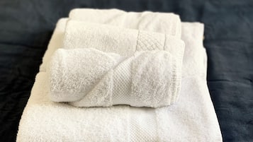 Une serviette blanche, soigneusement pliée, posée sur un couvre-lit bleu foncé.