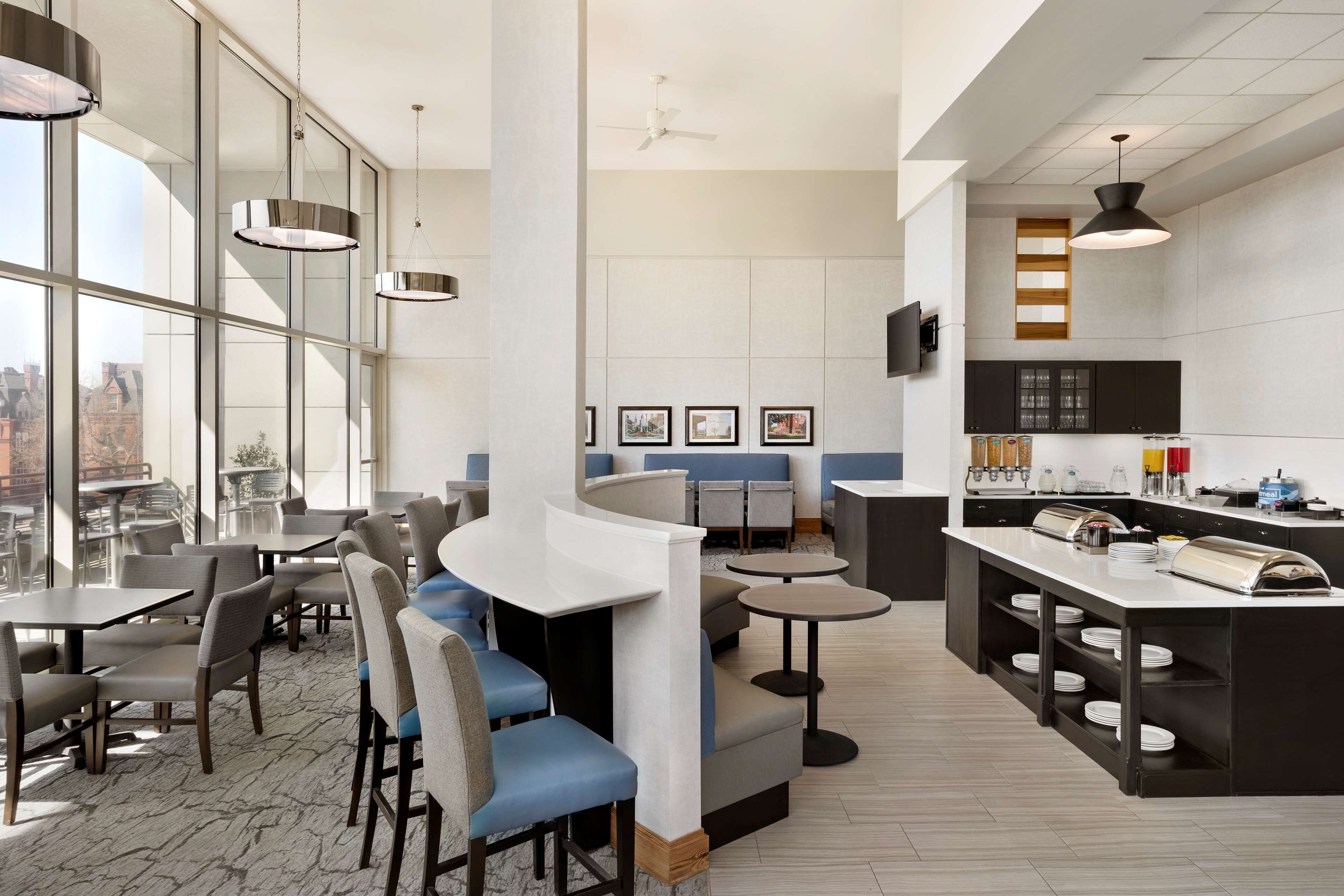 Un restaurante moderno con techos altos, ventanas amplias y una variedad de opciones de asientos, incluyendo mesas y cabinas.