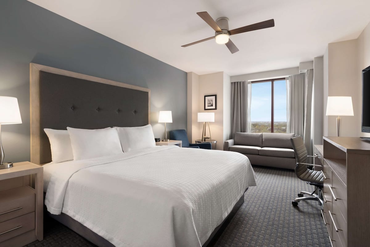 Une chambre d’hôtel avec un grand lit, un bureau avec une chaise, un canapé et un téléviseur.
