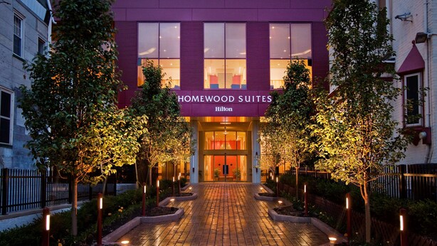 Entrada de un hotel con un cartel que dice "Homewood Suites Hilton".