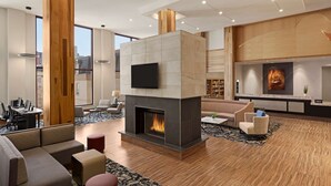Un moderno vestíbulo de hotel con chimenea, asientos cómodos, un televisor de pantalla plana y una mesa de recepción.