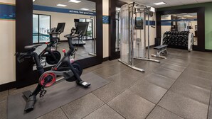 A gym with exercise equipment including a stationary bike, a weight machine, and dumbbells.