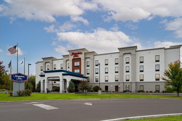 A Hampton Inn hotel with a modern facade, multiple entry points, and a clear sky.