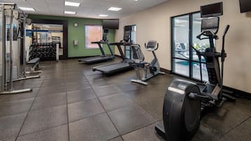 Une salle de sport équipée de tapis de course, de vélos elliptiques et de matériel de musculation.