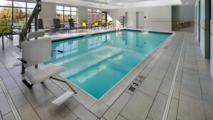 An indoor swimming pool with a lifeguard chair, poolside chairs, and a sunroof.