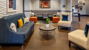 A modern lobby with a sofa, armchairs, a round table, and a bench.