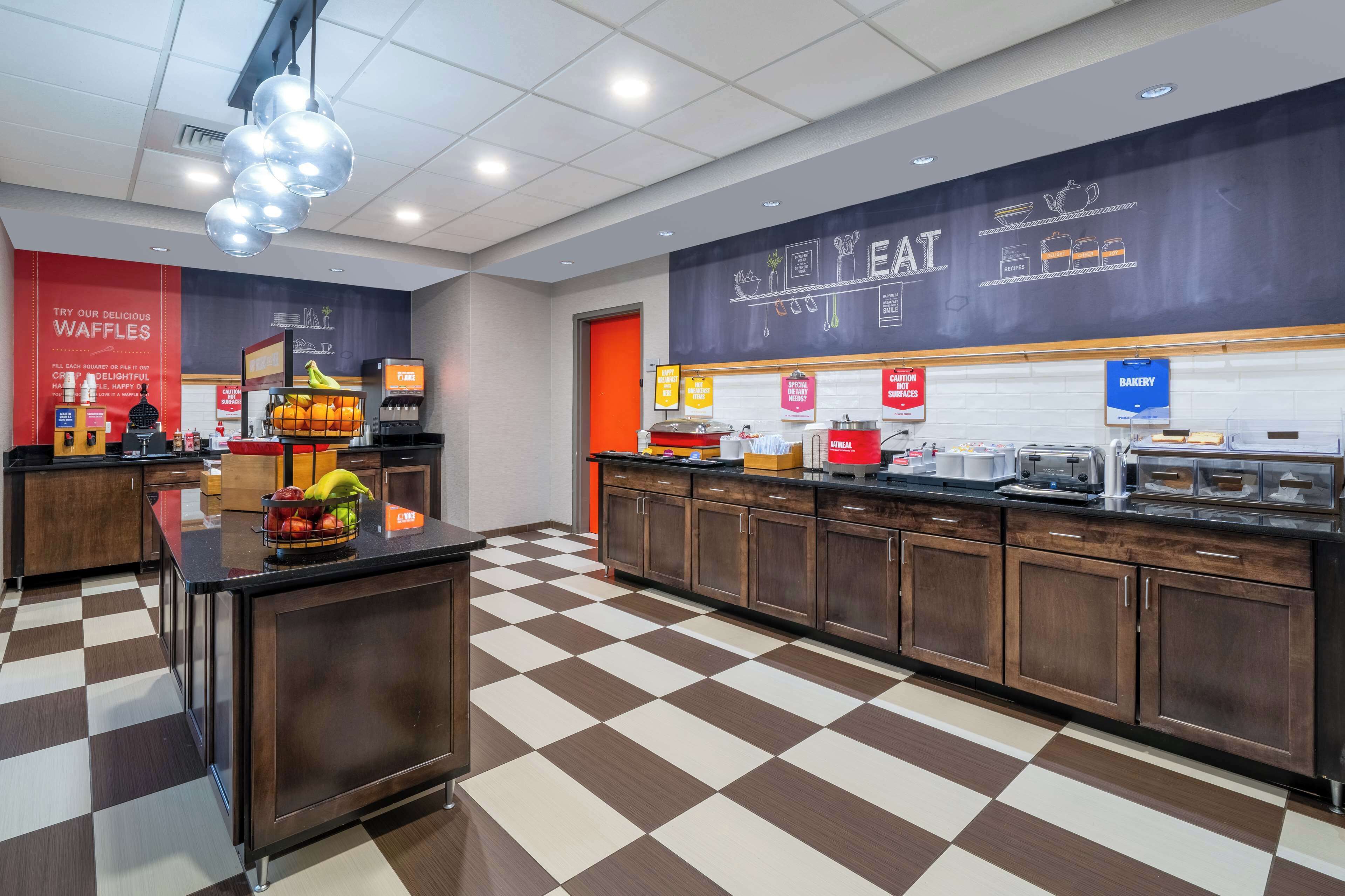 A modern kitchen area with a checkered floor, a waffle station, and a bakery section.