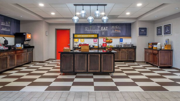 A modern kitchen area with a checkered floor, a central island, and a bright red door. - Hampton Inn Dahlgren (King George)