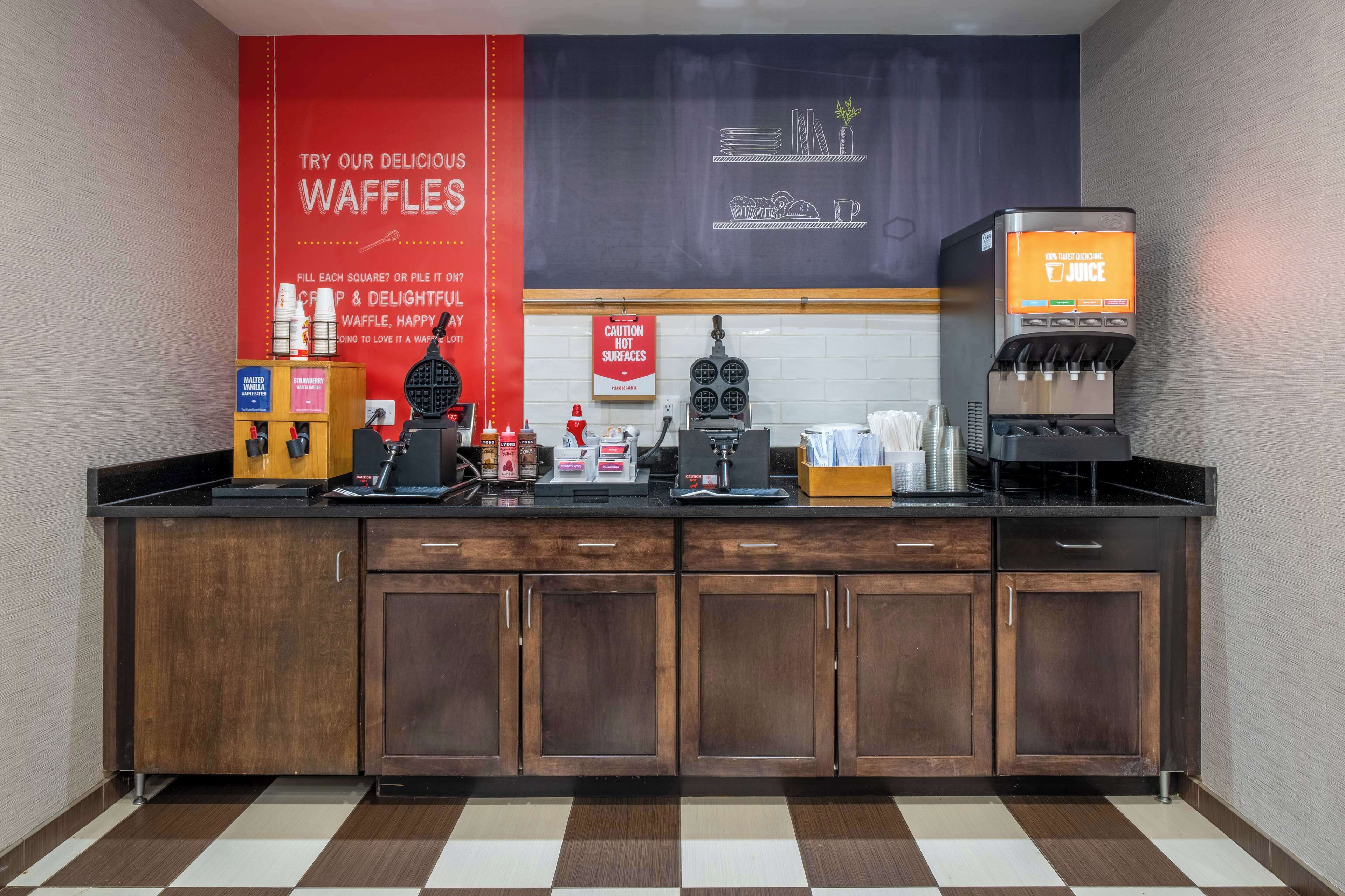 Una kitchenette equipada con una máquina para hacer gofres, una cafetera y un dispensador de jugo.