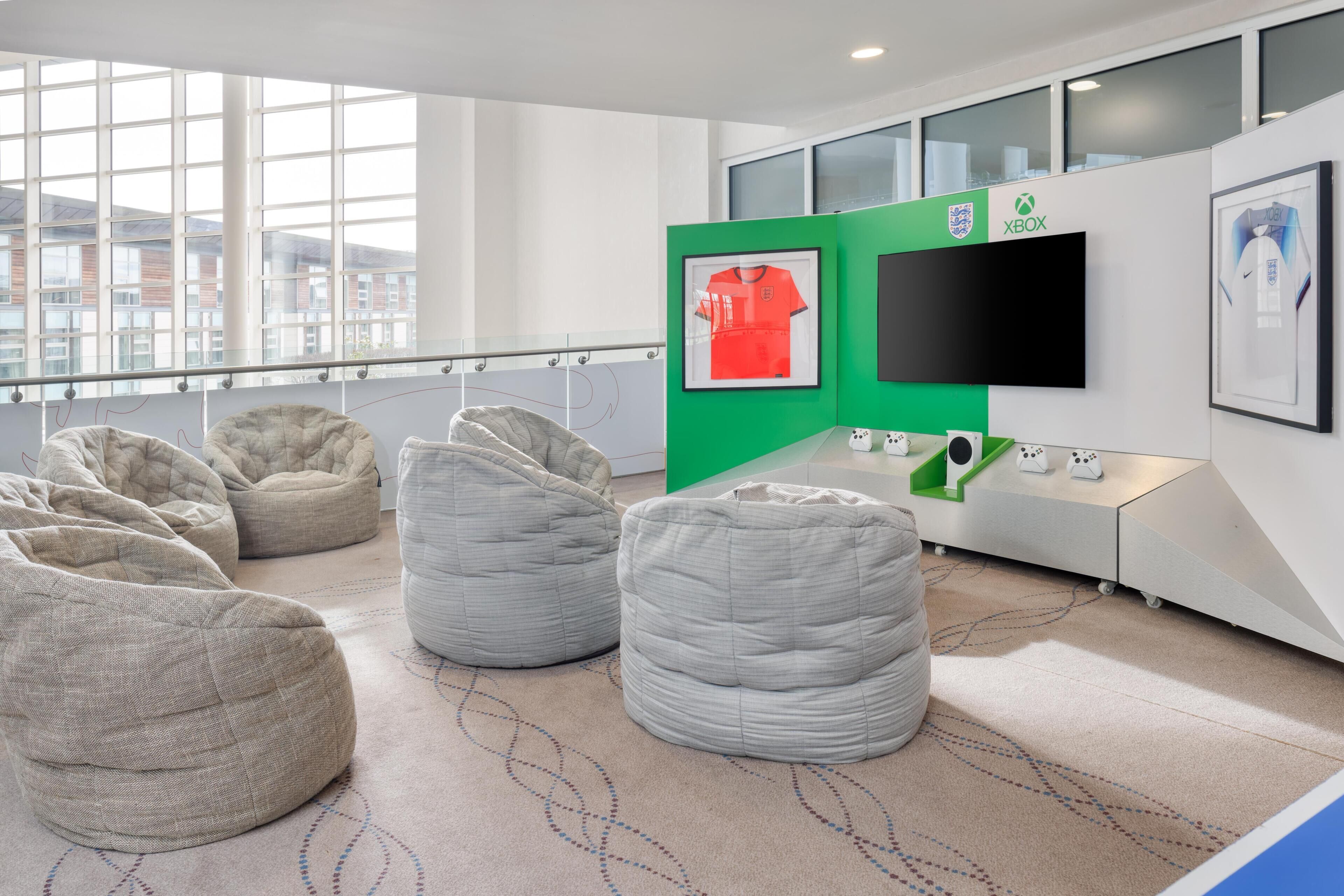 A modern room with bean bags, a TV, and framed sports jerseys.