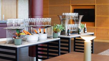 Un comedor moderno con varias mesas, cada una con copas de vino, botellas y macetas.