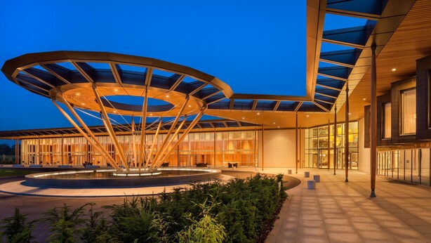 A modern building with a circular glass structure, a courtyard, and a well-lit entrance. - Hilton at St George's Park, Burton Upon Trent (Burton on Trent)