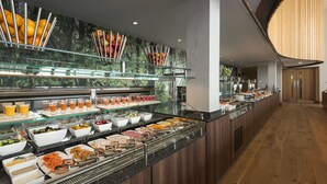 A buffet with various food options, a glass display case, and a wooden panel wall. - Hilton at St George's Park, Burton Upon Trent (Burton on Trent)