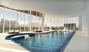 Una piscina interior moderna con paredes de vidrio transparente, que ofrece vistas panorámicas del paisaje circundante.