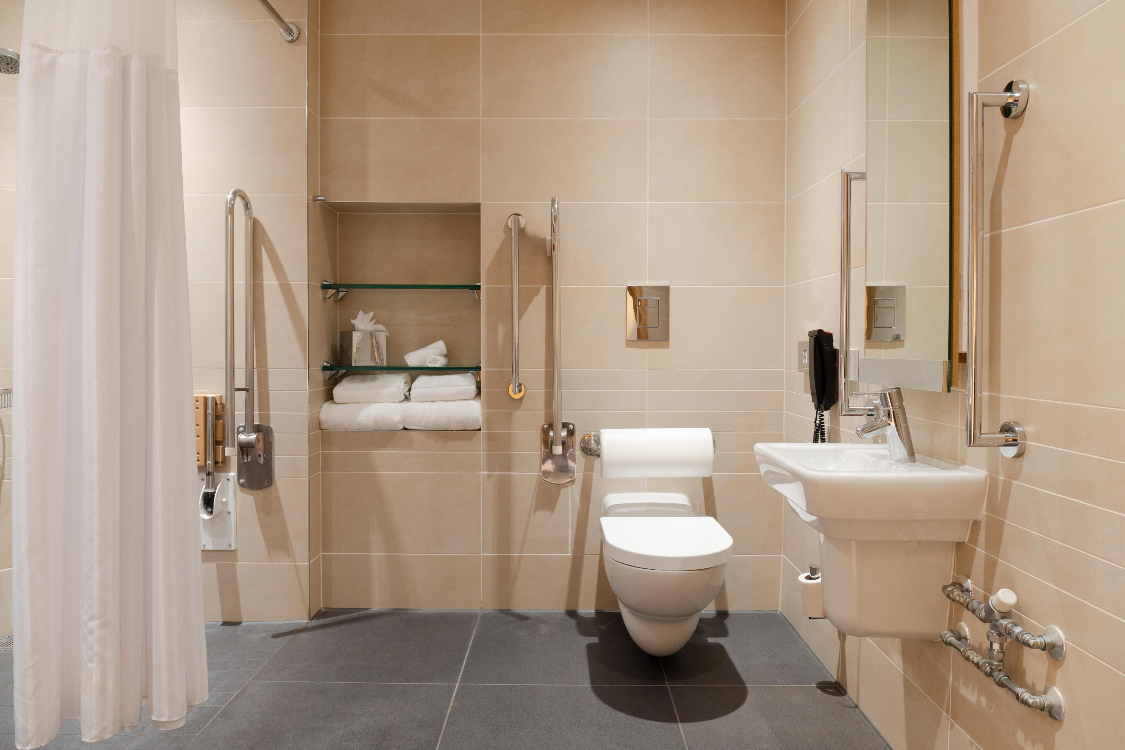 A modern bathroom with a toilet, sink, and glass shelves with towels.