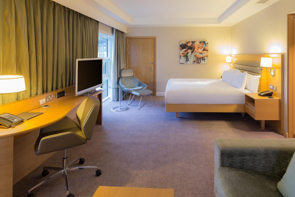 Une chambre d’hôtel avec un lit, un bureau, une chaise, une télévision et un tableau au mur.