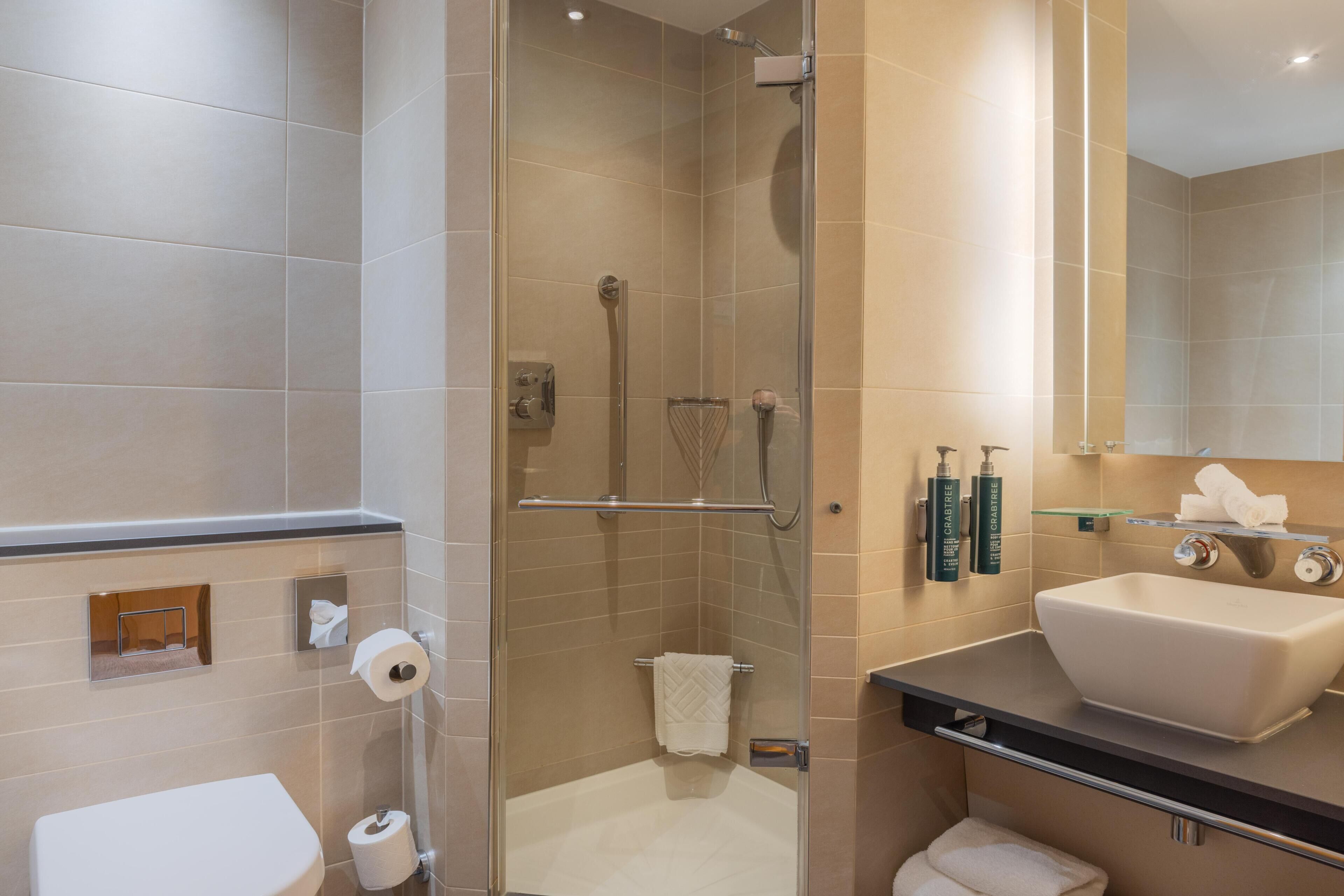 A modern bathroom with a glass-enclosed shower, a white sink, and a mirror above the sink.