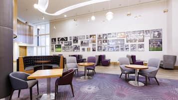 Ein stilvoller Lounge-Bereich mit Sitzgelegenheiten, einer Wand mit gerahmten Fotos und einer Decke mit integrierter Beleuchtung.