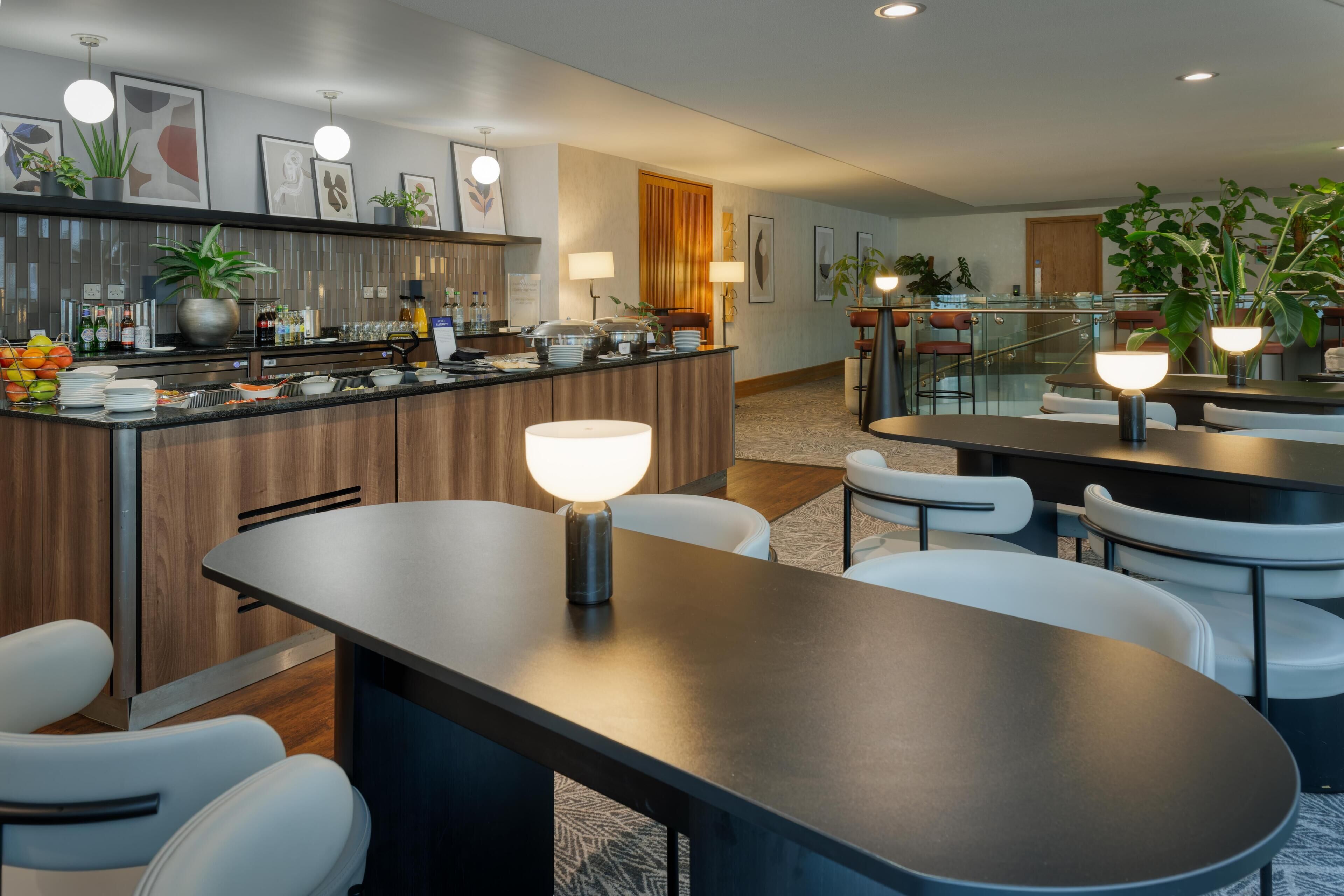A modern hotel lobby with a bar area, seating, and decorative plants.