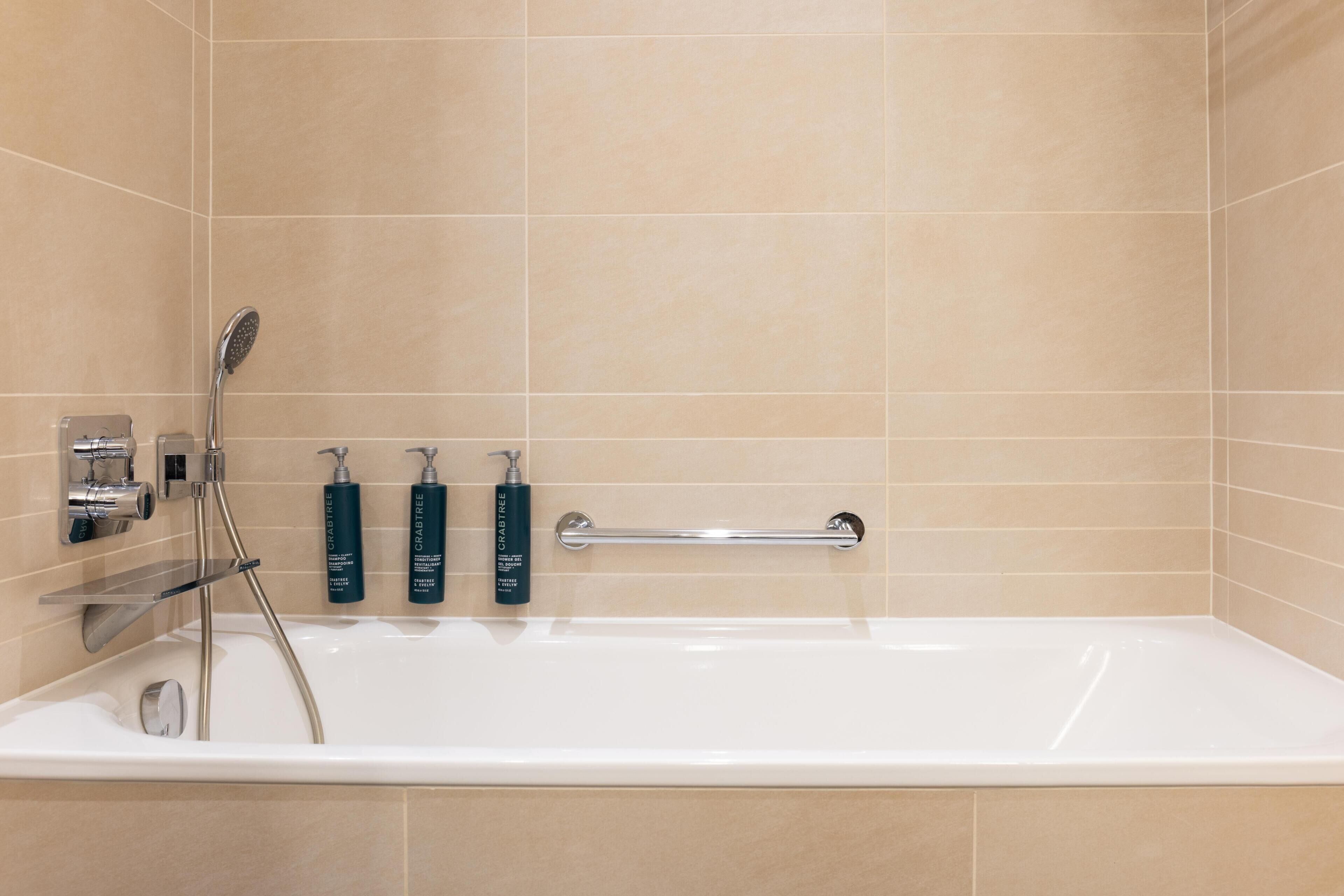 Ein modernes Badezimmer mit einer Badewanne, einer Duschbrause und zwei Seifenspendern.