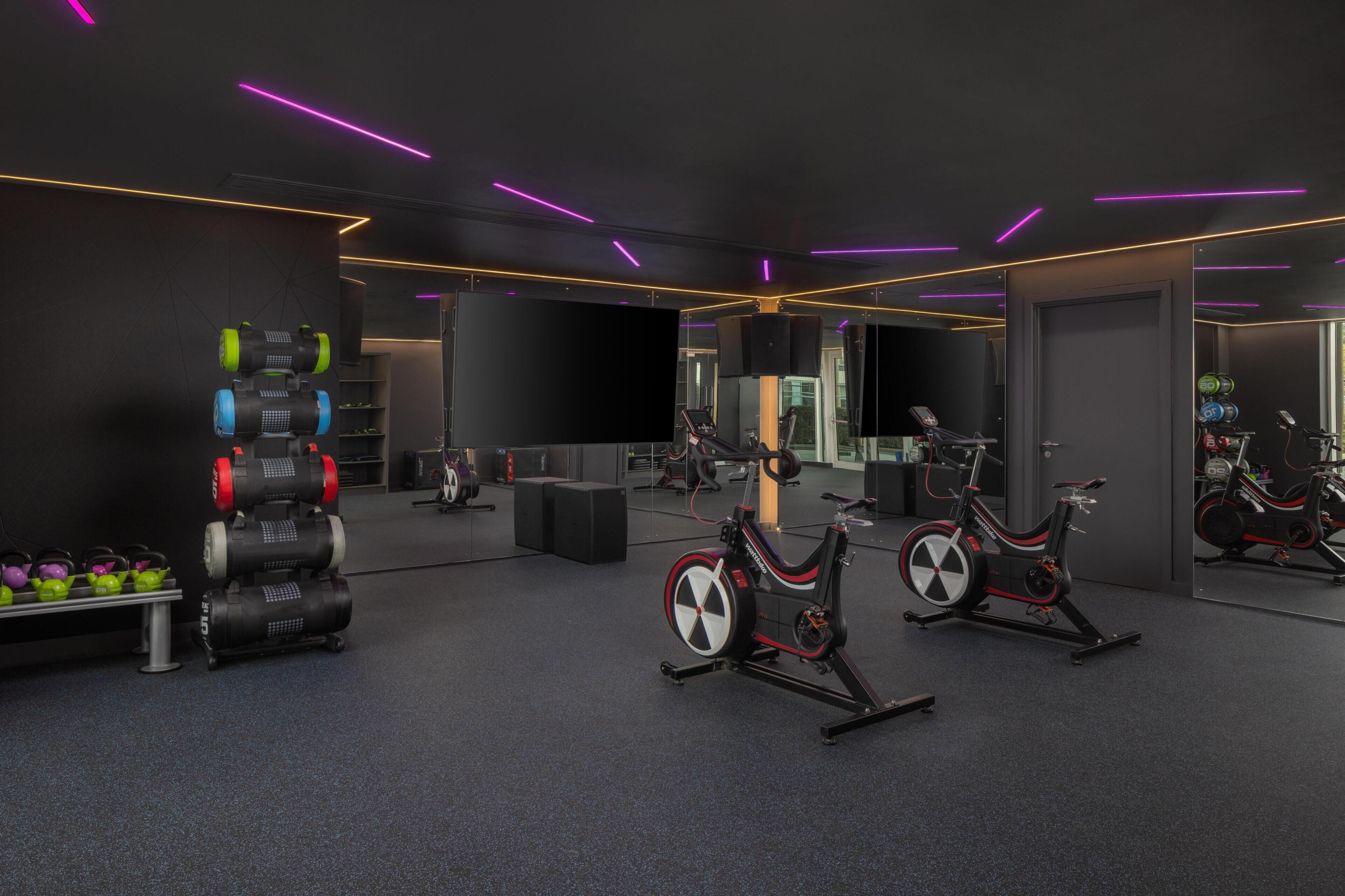 A gym with exercise equipment, mirrors, and a dark color scheme.
