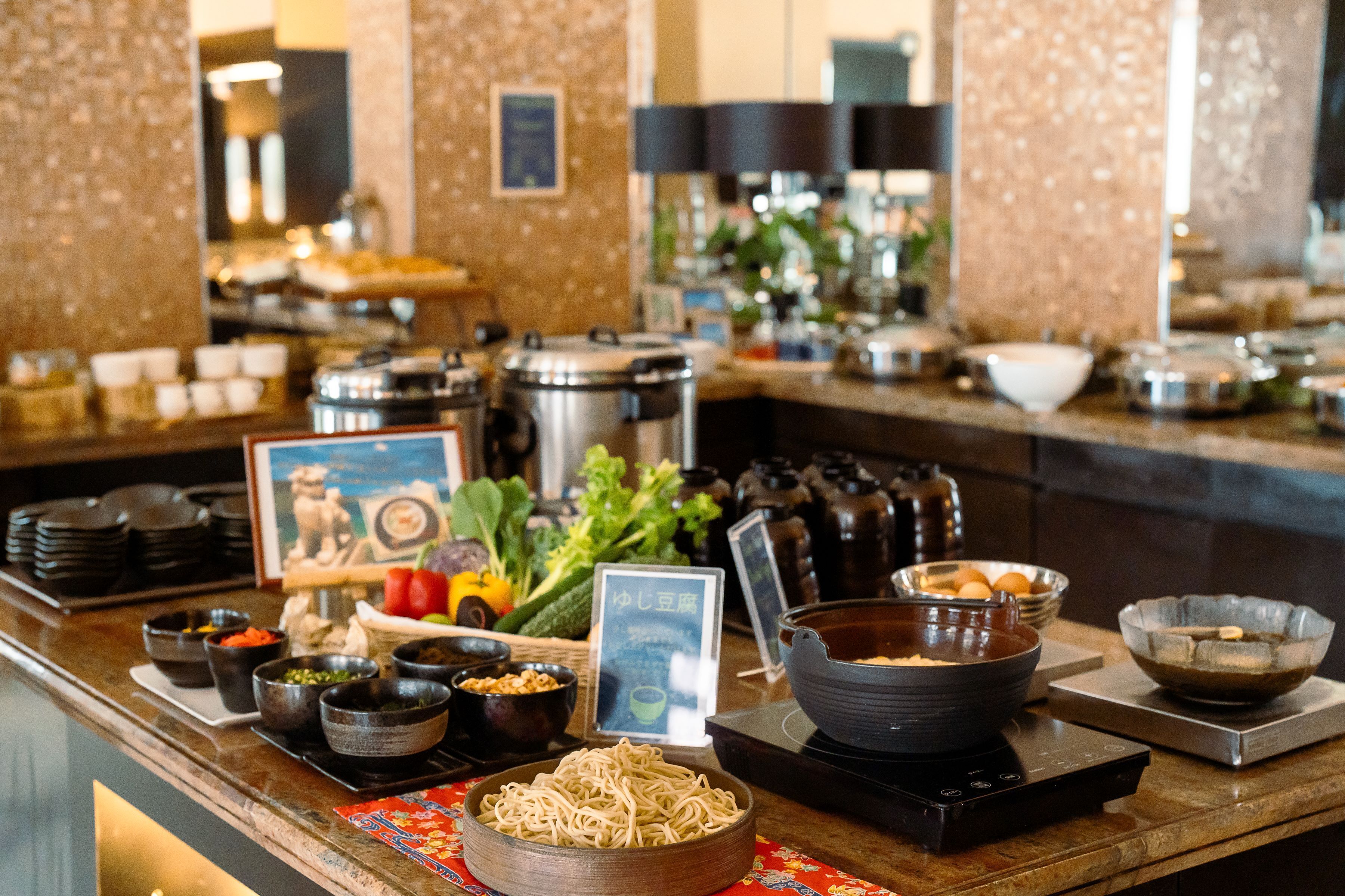 A buffet setup with various food items and cooking equipment.
