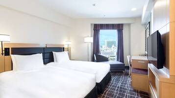 A hotel room with a large bed, a desk, a television, and a window with a city view.
