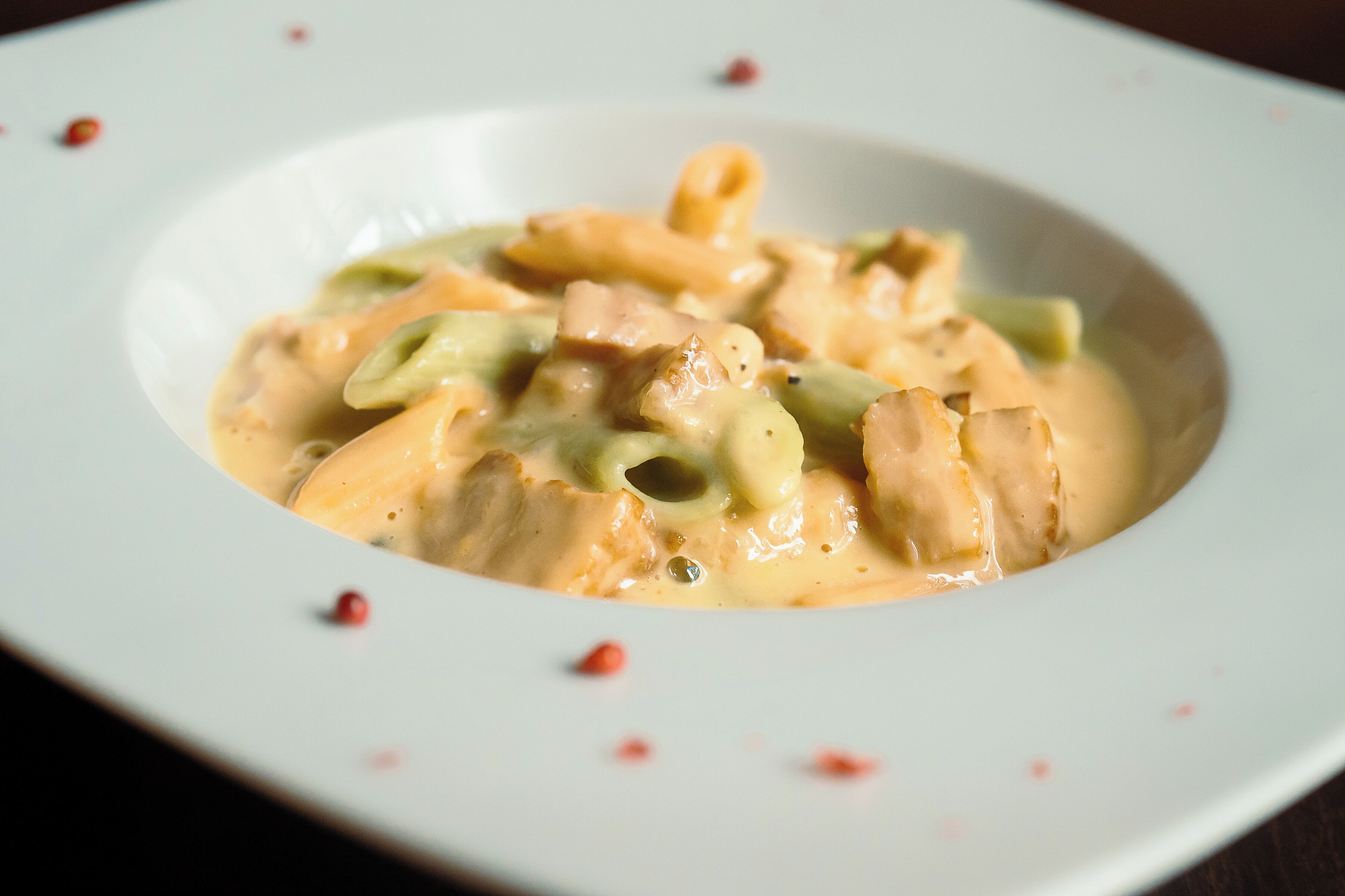 A bowl of pasta with a creamy sauce and green vegetables.